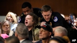 A protester is removed during a Senate Armed Services Committee confirmation hearing for Pete Hegseth, President-elect Donald Trump's choice to be Defense secretary, at the Capitol in Washington, Jan. 14, 2025.