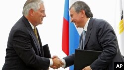 FILE - Igor Sechin, CEO of state-controlled Russian oil company Rosneft, right, and Exxon Mobil Corp. CEO Rex Tillerson shake hands after signing an agreement at the Black Sea port of Tuapse, southern Russia, June 15, 2012. 