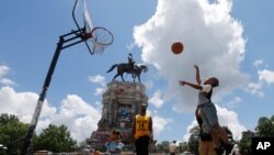 Isaiah Bowen, right, takes a shot as his dad, Garth Bowen, center, looks on at a basketball hoop in front of the statue of Confederate General Robert E. Lee on Monument Avenue in Richmond, Virginia, June 21, 2020.