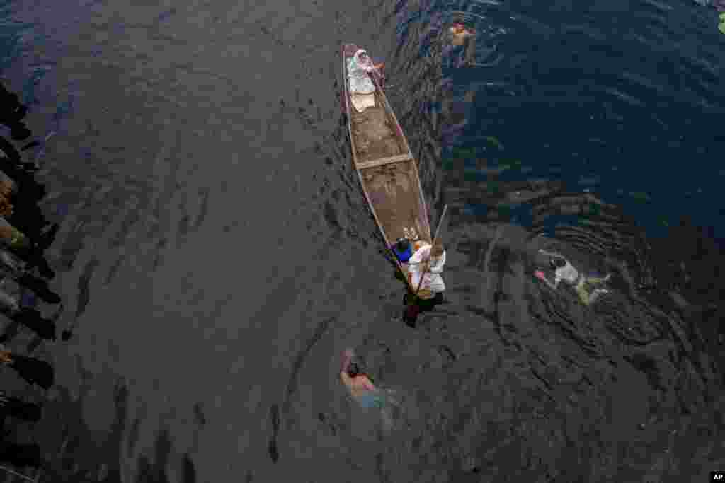 A Kashmiri family row their shikara, or traditional boat, as boys swim in the Nageen Lake on the outskirts of Srinagar, Indian-controlled Kashmir.