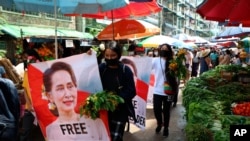 Anti-coup protesters walk through a market with images of ousted Myanmar leader Aung San Suu Kyi at Kamayut township in Yangon, Myanmar Thursday, April 8, 2021. They walked through the markets and streets of Kamayut township with slogans to show…