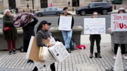 Sejumlah warga membawa plakat dalam aksi solidaritas terhadap para pekerja Badan Pembangunan Internasional AS (USAID) yang dipecat di Washington, pada 27 Februari 2025. (Foto: Reuters/Nathan Howard)