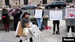 Sejumlah warga membawa plakat dalam aksi solidaritas terhadap para pekerja Badan Pembangunan Internasional AS (USAID) yang dipecat di Washington, pada 27 Februari 2025. (Foto: Reuters/Nathan Howard)