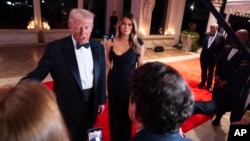 Melania Trump gleda kako novoizabrani američki predsjednik Donald Trump razgovara s novinarima prije novogodišnje zabave u Mar-a-Lagu 31. decembra 2024. u Palm Beachu na Floridi. Trump je rekao novinarima da planira prisustvovati sahrani bivšeg predsjednika Džimija Kartera.