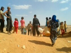 FILE - Syrian refugees gather for water at the Rukban camp for displaced Syrians, on the Jordan and Syria borders, June 23, 2016.