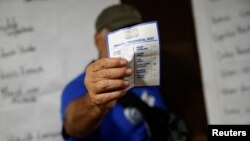 (FILE) A volunteer holds a ballot paper in Venezuela.