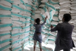 Workers handle sacks of wheat flour at a World Food Program food aid distribution center in Sanaa, Yemen, Feb. 11, 2020.