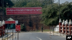 A soldier stands guard at a checkpoint next to a military propaganda billboard in Mandalay, Myanmar, Feb. 3, 2021.