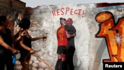 Las mujeres señalan un mural que representa la controversia sobre un beso del jefe de la FA española, Luis Rubiales, a la jugadora Jenni Hermoso durante las celebraciones de la Copa del Mundo, en una pared del Glòries Park en Barcelona, España, el 4 de septiembre de 2023.