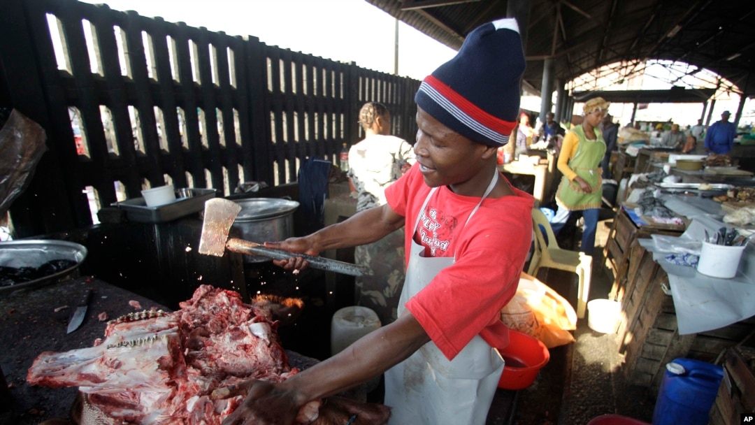 FILE - A butcher cuts a cows head at the early morning market
