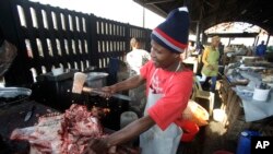 FILE - A butcher cuts a cows head at the early morning market