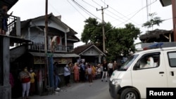 Seorang sukarelawan mengenakan APD terlihat di dalam ambulans, mengangkut korban COVID-19 yang meninggal dunia saat isoman di rumahnya, disaksikan penduduk setempat dari kejauhan di lingkungan Mulyaharja, Bogor, Jawa Barat, 8 Juli 2021. (REUTERS/Willy Kurniawan)