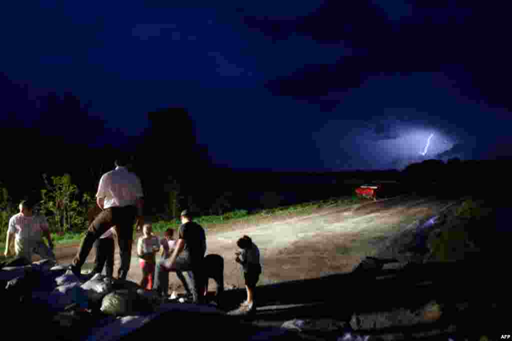 Volunteers place sandbags atop a temporary levee to fight back floodwaters in Dutchtown, Missouri. Powerful storms swept through the nation's midsection and pushed river levels to dangerous heights, threatening to flood several towns in Missouri. (AP Phot