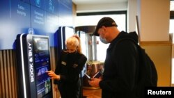 An employee helps a person buy a ticket inside the Odeon Luxe Leicester Square cinema, on the opening day of the film "Tenet", amid the coronavirus disease (COVID-19) outbreak, in London, Britain, Aug. 26, 2020.