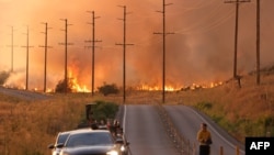 Un hombre se para en una carretera cerca de las llamas del incendio Rabbit en Moreno Valley en el condado de Riverside, California, el 14 de julio de 2023.