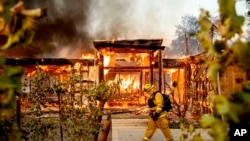 Woodbridge firefighter Joe Zurilgen passes a burning home as the Kincade Fire rages in Healdsburg, California, Oct 27, 2019. 
