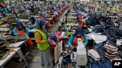 FILE - Workers sit in their stations at factory in Bandung, West Java province, Indonesia, July 11, 2024. The ILO says the global labor income share had fallen by 1.6 percentage points since 2004.