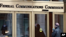 FILE - In this Dec. 14, 2017, file photo, a person enters the Federal Communications Commission building in Washington. 