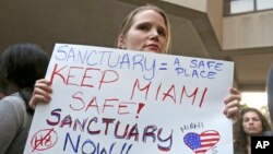 FILE - Protester Jennifer Smith-Camejo holds a sign during a rally in downtown Miami, Jan. 31, 2017. 