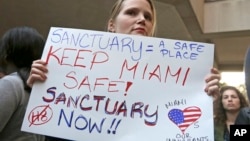 FILE - Protester Jennifer Smith-Camejo holds a sign during an anti-Trump and anti-Gimenez rally in downtown Miami.