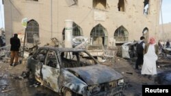 Des gens passent l'épave d'une voiture bombardée à l'extérieur du Musée de Raqqa, après des frappes aériennes que les défenseurs des droits de l'homme attribuent aux forces fidèles au président Bachar al-Assad de la Syrie à Raqqa, Est de la Syrie, contrôlé par l'Etat islamique, le 25 novembre 2014.