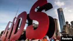 FILE - Flowers are laid as tributes to those killed in the Malaysia Airlines flight MH17, at the base of a large sign for the 20th International AIDS Conference in Melbourne, Australia, July 20, 2014. 