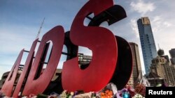 FILE - Flowers are laid as tributes to those killed in the Malaysia Airlines flight MH17, at the base of a large sign for the 20th International AIDS Conference in Melbourne, Australia, July 20, 2014. 