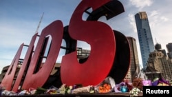 FILE - Flowers are laid as tributes to those killed in the Malaysia Airlines flight MH17, at the base of a large sign for the 20th International AIDS Conference in Melbourne, Australia, July 20, 2014. 