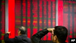 In this Oct. 31, 2018, photo, Chinese investors monitor stock prices at a brokerage house in Beijing. China's government is trying to dispel stock market gloom and talk prices back up with promises of tax cuts and a media campaign led by its economic czar. 