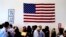 FILE - People file past the U.S. flag and a portrait of President Barack Obama on their way to attend a naturalization ceremony in Irving, Texas. 
