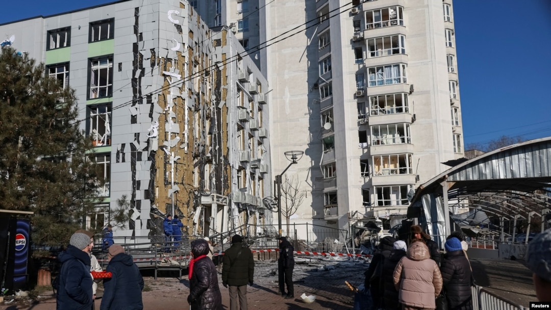 Жители стоят у дома пострадавшего от удара беспилотника, в Одессе, Украина, 19 февраля 2025 года.