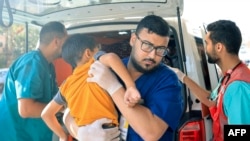 FILE - Rescuers bring a Palestinian boy to a hospital following an Israeli strike, in Khan Yunis in the southern Gaza Strip on October 14, 2023.