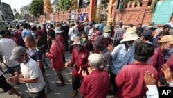 Three-wheeled pedicab drivers sanitize their hands with alcohol while waiting for customers in Phnom Penh, Cambodia, Friday, March 27, 2020. (AP Photo/Heng Sinith)