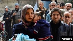 Residents line up to receive humanitarian aid at the Palestinian refugee camp of Yarmouk, in Damascus, Syria, March 11, 2015. 