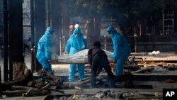 Health workers in personal protective equipment carry the body of a COVID-19 victim for cremation in New Delhi, India, Nov. 19, 2020.