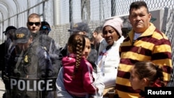 A group of Cubans hoping to apply for asylum, wait in front of U.S. Customs and Border Protection (CBP) agents on an international bridge at the border between Mexico and the U.S., in Ciudad Juarez, Mexico, March 31, 2019.