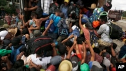 Central American migrants, part of one of the caravans hoping to reach the U.S. border, scramble to get a ride on a truck, in Isla, Veracruz state, Mexico, Nov. 3, 2018. The 150 buses that the governor of Veracruz promised to the migrants to get to Mexico City did not arrive.