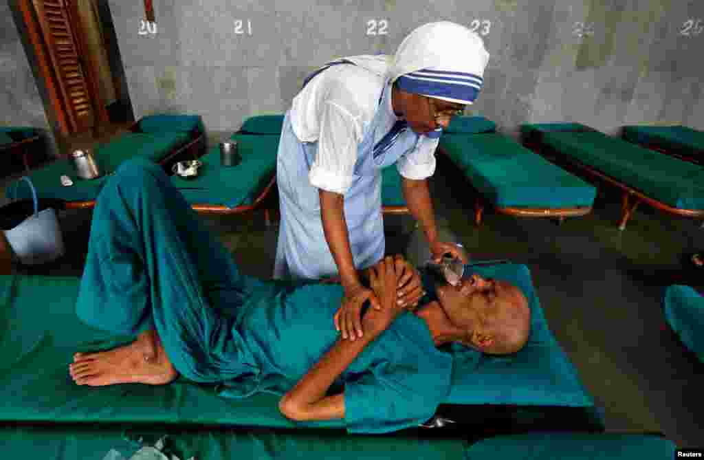 A nun belonging to the global Missionaries of Charity tends to a patient at Nirmal Hriday in Kolkata, India, a home for the destitute and old, founded by Mother Teresa, ahead of Mother Teresa's canonization ceremony.