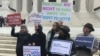 Activists rally outside the U.S. Supreme Court ahead of arguments in a key voting rights case involving a challenge to Ohio's policy of purging infrequent voters from voter registration rolls, in Washington, Jan. 10, 2018. 