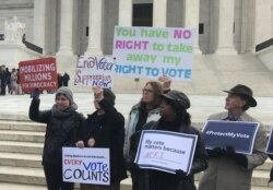 Activists rally outside the U.S. Supreme Court ahead of arguments in a key voting rights case involving a challenge to Ohio's policy of purging infrequent voters from voter registration rolls, in Washington, Jan. 10, 2018.
