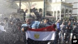 Des manifestants face aux canons à eau, au Caire
