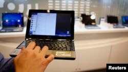 An employee poses with the low-cost Asus Eee PC laptop inside a mall in Taipei February 25, 2009. Netbooks have made headlines since their 2007 launch, making PCs accessible to millions of non-traditional users. But their cheap cost could also carry a ste