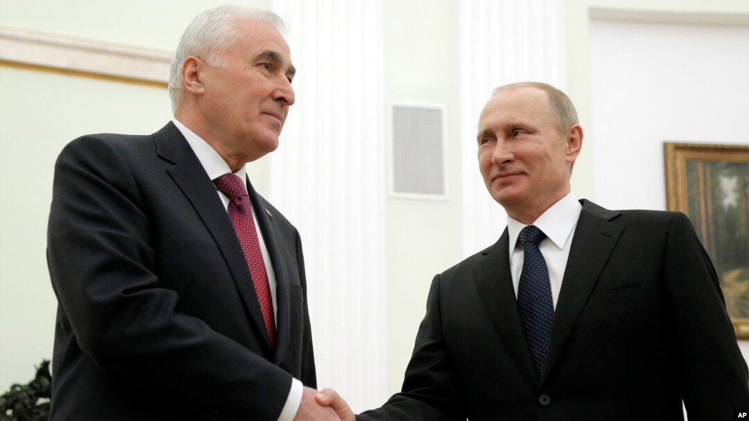 Russian President Vladimir Putin, right, and the leader of Georgia's breakaway province of South Ossetia Leonid Tibilov shake hands during their meeting in the Kremlin in Moscow, Russia, March 18, 2015.
