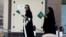 Saudi women hold national flags as they walk on a street during Saudi National Day in Riyadh, Saudi Arabia, Sept. 23, 2016. 