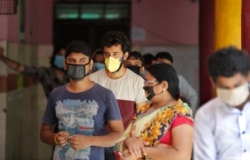 People wait in a queue for the COVID-19 rapid antigen test in New Delhi, India, June 24, 2020.