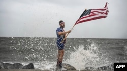 Jutjuber Mark Pejton drži američku zastavu dok pozira svom bratu Metu Pejtonu na obali uoči dolaska uragana Helene u Aligator Point, Florida, 26. septembra 2024.