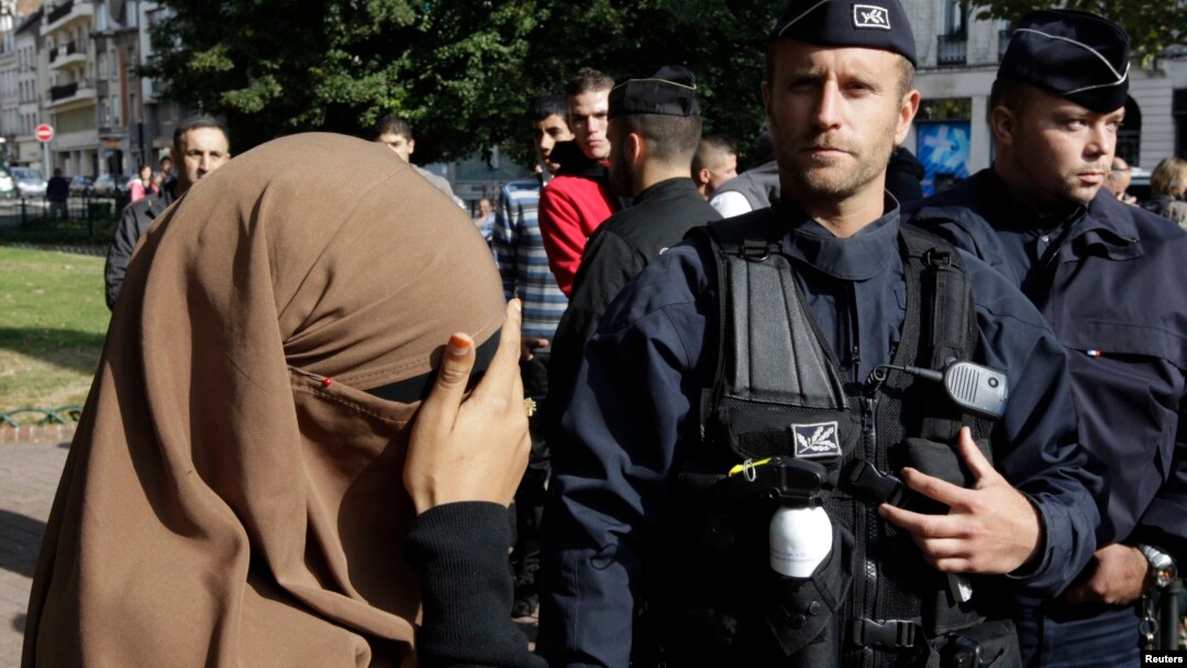 Seorang perempuan yang mengenakan jilbab dan cadar menutup matanya saat berada di dekat polisi Perancis (foto: dok). 