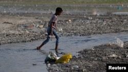 A boy crosses a drain on the banks of the river Ganges in Kanpur, India, April 4, 2017.