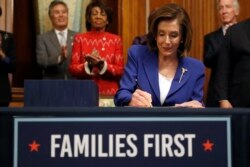 House Speaker Nancy Pelosi of California signs the Coronavirus Aid, Relief and Economic Security (CARES) Act. after it passed in the House on Capitol Hill, March 27, 2020, in Washington.