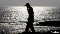 FILE - An Israeli soldier speaks on a mobile phone with his mother while walking alongside a beach near the city of Nahariya.